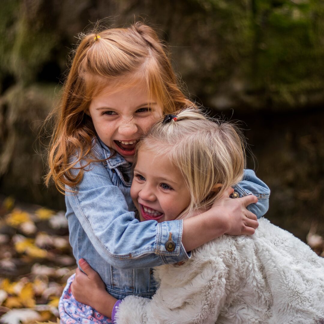 two girls hug each other with wide smiles on their faces