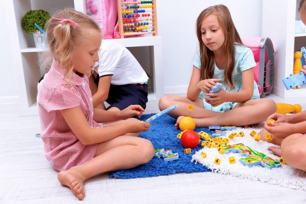 small group of girls age 8 sit together on the floor playing the board game