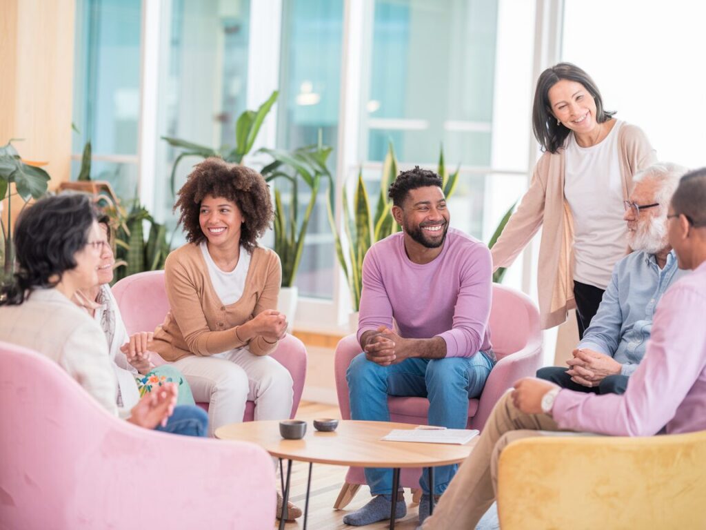 A photo of a small group of diverse parents in a supportive setting, such as a living room or community center, smiling and sharing stories.